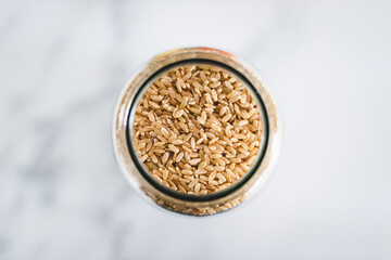 brown rice in clear pantry jar on marble background, simple ingredients concept