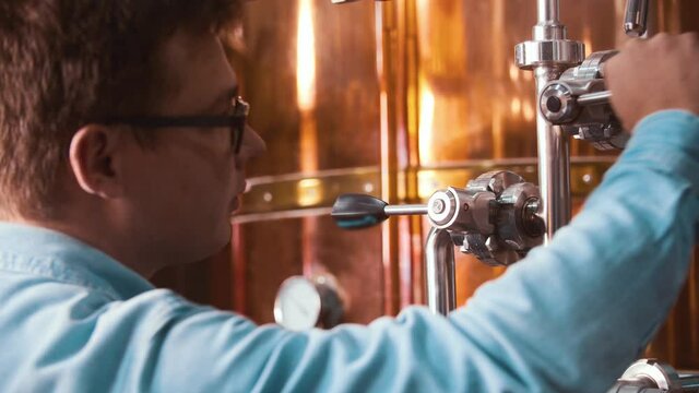 A man in a brewery clings the valves