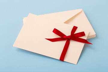 Letter with red bow ribbon on stack of envelope