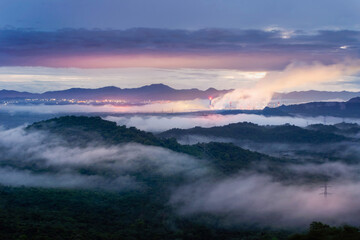 Aerial view mist after the rain on the mountain high voltage pole and steam from a coal power plant at sunset, Pang Puey, Mae Moh, Lampang, Thailand. Energy and environment concept. Long exposure.
