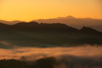 Fototapeta na wymiar Beautiful fog and golden light in the morning forest with green mountains. Baan Jabo, Mae Hong Son, Thailand.