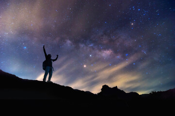 Landscape with Milky Way. Night sky with stars and silhouette of a standing happy man on the...