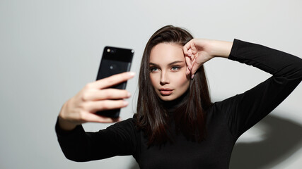 Naklejka premium beautiful young woman taking selfie on smartphone