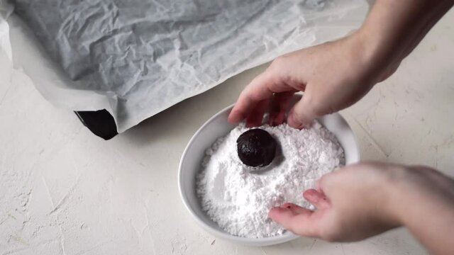 Making Chocolate Crinkle Cookies. Woman Is Rolling The Ball Of Dough In Sugar Powder And Is Putting It On The Oven Tray With Parchment Paper. Baking At Home