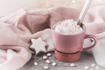 Cup of coffee or hot chocolate with cream and marshmallows on gray and pink background