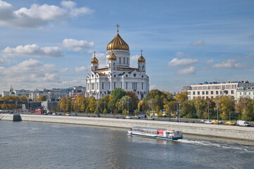 Moscow, Russia - September 29, 2021: Autumn view of the Cathedral of Christ the Savior, the Prechistenskaya embankment and a pleasure boat sailing along the Moscow-River