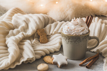 Gray cup of coffee or hot chocolate with cream, cinnamon and christmas cookies, fairy light in the background