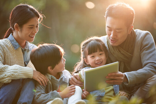 happy asian family having a good time outdoors in city park