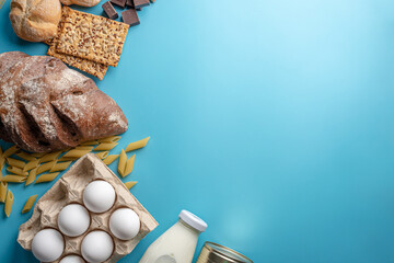 Fresh food on a blue background top view. Bread, chocolate, milk, eggs and other products with home delivery. Copy space
