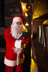 Santa with a book in his hands against the background of a bookcase with a white beard in a red suit