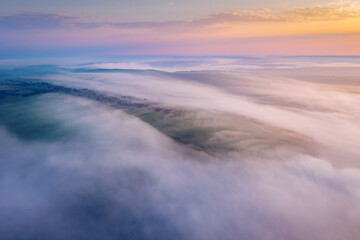 Fantastic scene of hills in the fog from a bird's eye view. Aerial photography, drone shot.