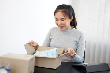 Shopping online concept a smiling woman unboxing an arriving parcel to check the products she bought after waiting with an effort