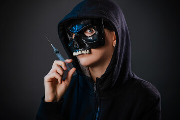 Drug addiction concept. Fear of vaccinations and injections. A person in a sweatshirt with a hood...