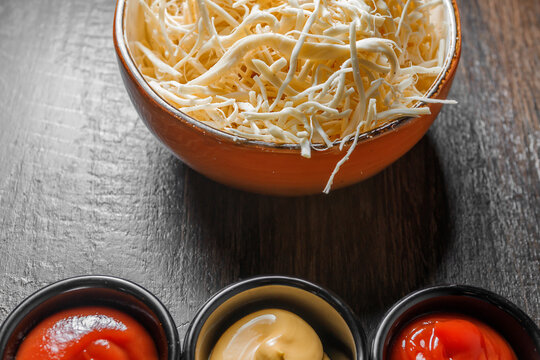 Fibrous chechil cheese in a deep cup stands on a wooden table.