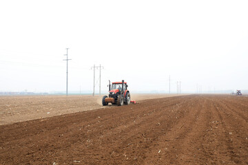 Obraz premium Farmers drive tractors to level up the land for planting corn on the farm.