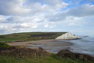 The great views from the top of the Seven Sisters chalk cliffs and national hillsides park with cloudy blue sky- East Sussex, United Kingdom