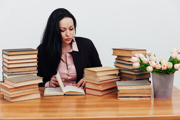 beautiful brunette woman in a business suit learns to read books at the table