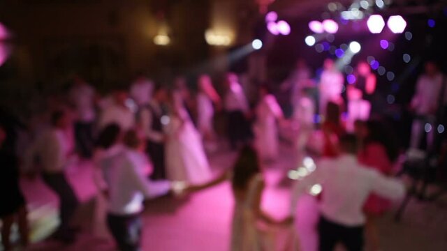 Blurred video. People dance in a circle at the wedding, holding hands.