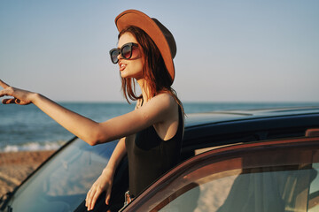 Naklejka premium cheerful woman in sunglasses and a hat on the ocean near the car