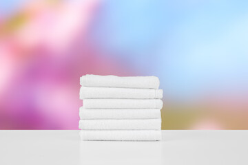 Stacked white spa towels on table against blurred background