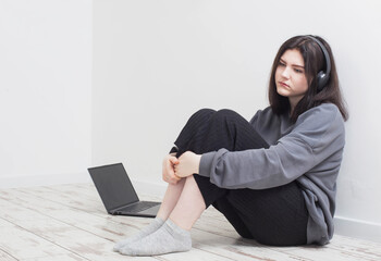 sad teenager girl with laptop sitting on floor