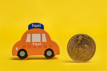 Coin in denomination of one American dollar and conventional symbolic taxi car on a yellow...