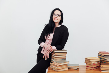 beautiful brunette woman in a business suit teacher with books at the table