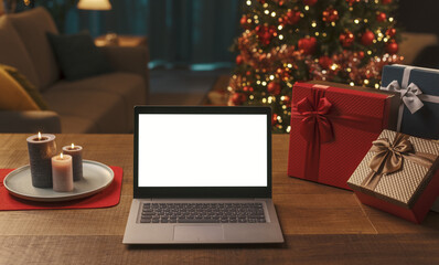 Laptop with blank screen, gifts and Christmas tree
