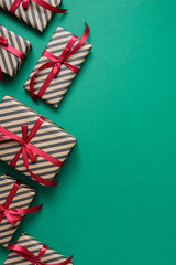 Fototapeta premium Striped craft gift box with black ribbon on a green. Valentines, Christmas or New Year day backdrop. Flat lay style with minimalistic design.