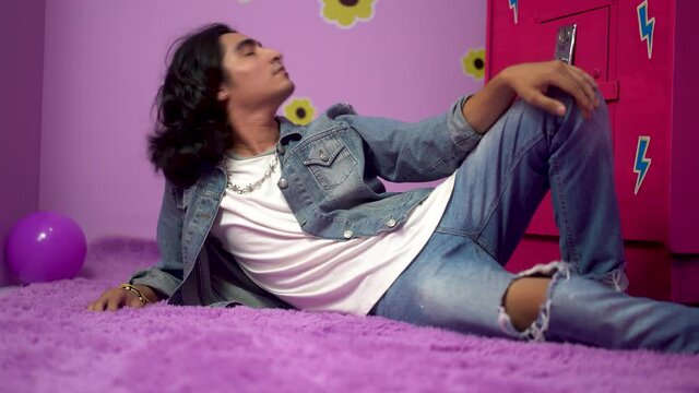 Beautiful latino man in seductive pose. Romantic video of non binary man lying on the carpet.