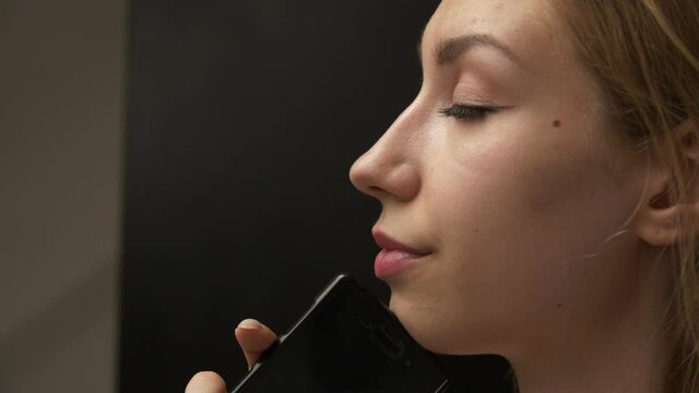 The idea of achieving comfort and satisfaction of desires through the use of online services. A young woman stands dreamily closing her eyes with her phone in her hand.