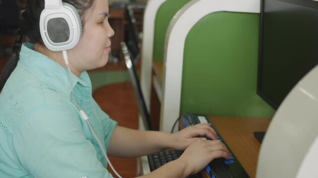Authentic blind person woman with headphone using computer with braille display assistive device for disabled people with visual impairment.