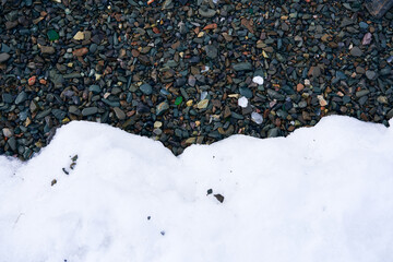 Close up photo of black rocks and pebbles and white snow