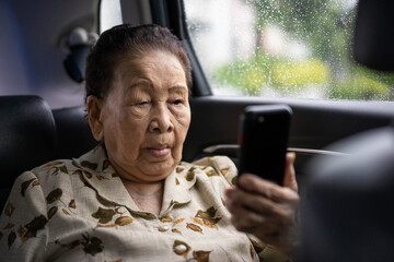 Very old Asian passenger woman age between 80 - 90 years old traveling by the car while raining and...