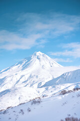 Winter landscape. Vilyuchinsky volcano covered with snow against blue sky. Kamchatka peninsula, Russia