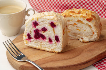 Biscuit roulade with cherry on wooden board