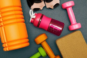 Toned flat lay template with fitness equipment, dumbbell, roller, bottle on the mat. Gym eqip and healthcare backgrounds