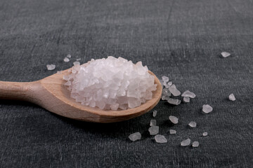 Pure white granular salt in a wooden spoon