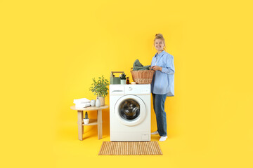 Concept of housework with washing machine and girl on yellow background