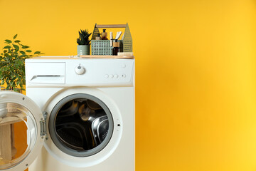 Concept of housework with washing machine on yellow background