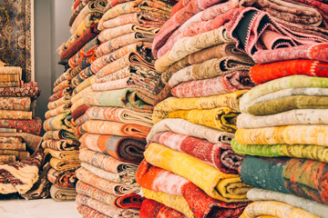 Stack of traditional oriental carpets and rugs as background with copy space. Multicolored ornamental carpets at carpet store. Popular touristic souvenir. Selective focus