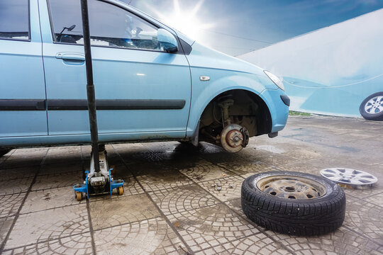 The passenger car stands on a jack lift with the wheel removed in the service. The process of replacing winter and summer tires. Nobody