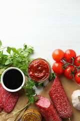 Сoncept of tasty food with salami sausage on white wooden background