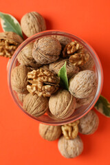Walnuts in glass jar on orange background