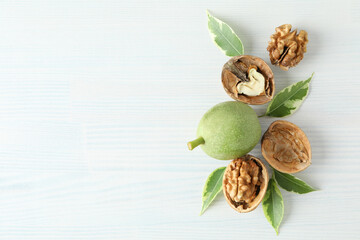 Walnuts with nut peel on white wooden background