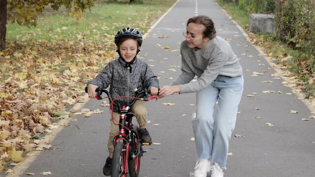 Happy Mother teaches child son to ride a bike on the bike path