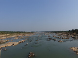Stone block of Golden color in the green waters of a mountain river.Trees and pine trees on the...