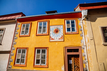 Obraz premium Kolin, Central Bohemia, Czech Republic, 10 July 2021: Narrow picturesque street with colorful renaissance baroque historical houses in medieval town center, sundial with the image of the sun