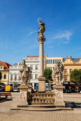 Fototapeta na wymiar Kolin, Central Bohemia, Czech Republic, 10 July 2021: Baroque Marian Column sandstone sculptural group with statues of four saints on Charles Square in medieval town center at sunny summer day
