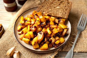 Fried potatoes in a plate on a gray wooden table closeup